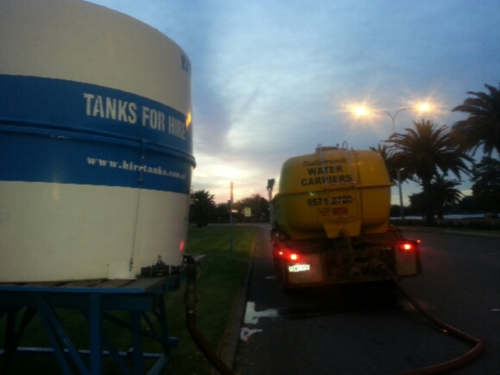 Water truck being refilled at dawn